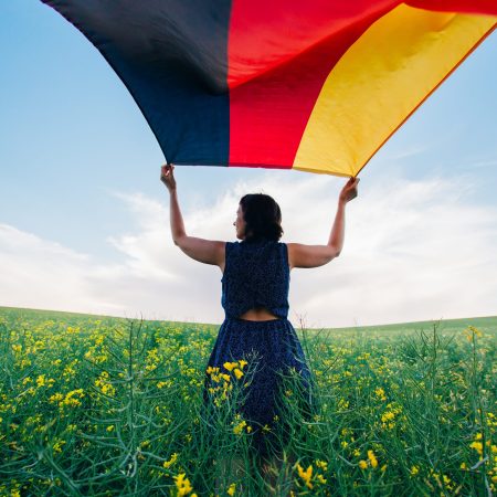 Woman holding the German flag outdoors on a meadow.